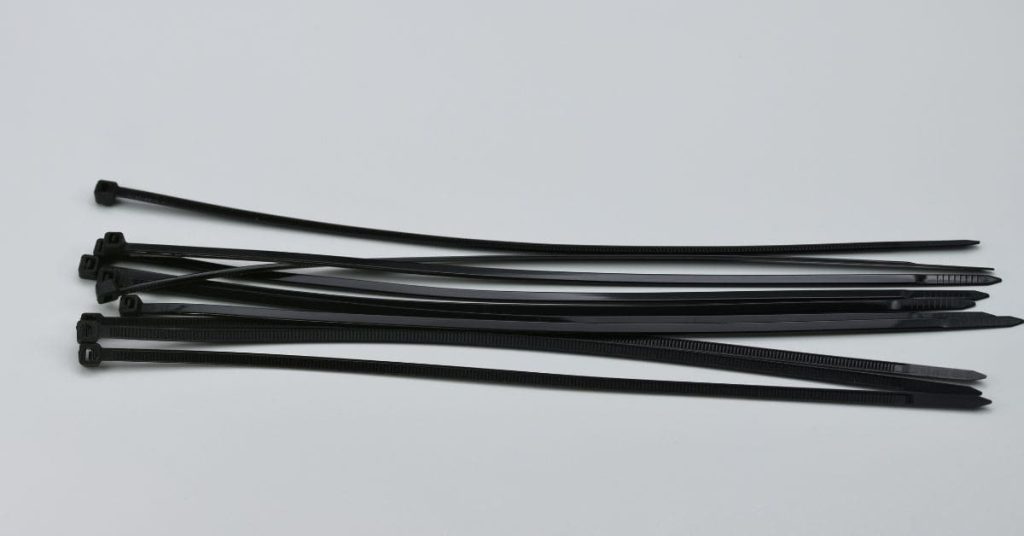 Black plastic cable ties of various lengths on white surface