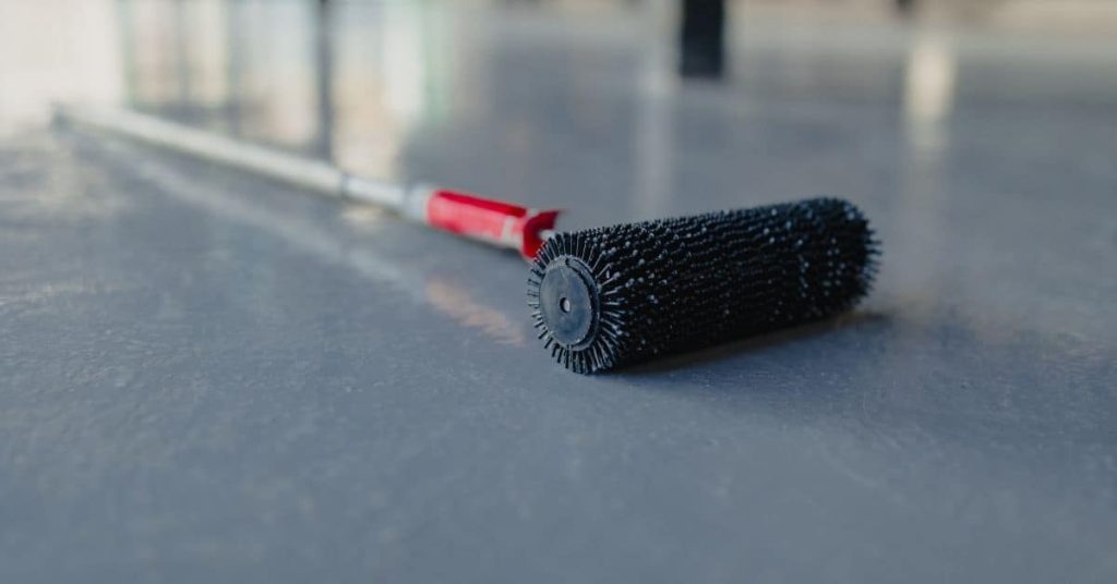 Black spiked roller with red handle on smooth floor surface