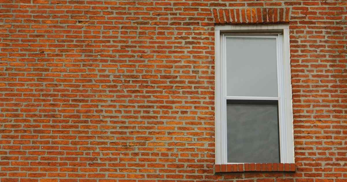 Brick wall with a white window and brick lintel above