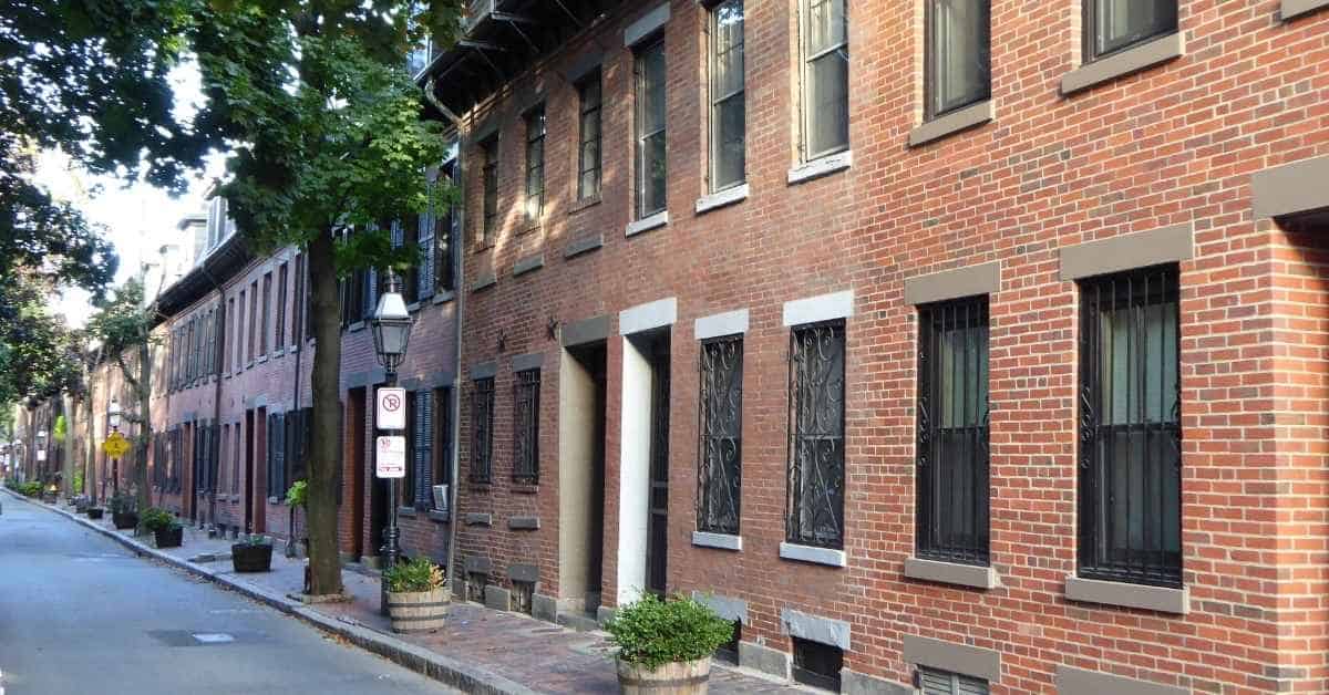 Row of red brick houses along a quiet street with trees