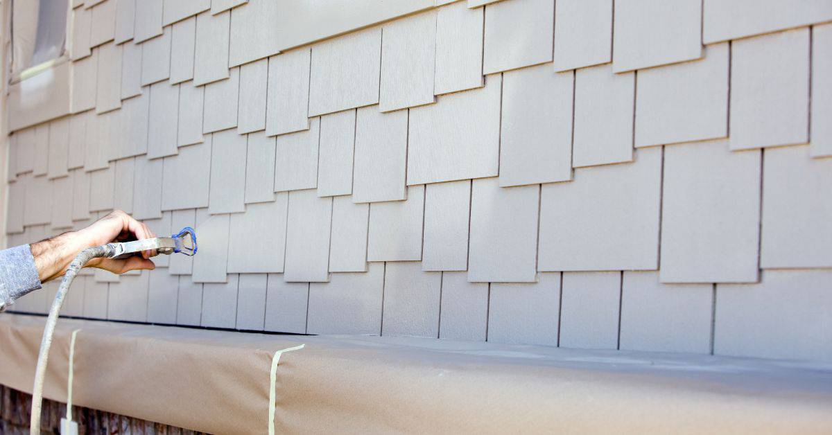 Hand spraying paint on exterior wooden shingles