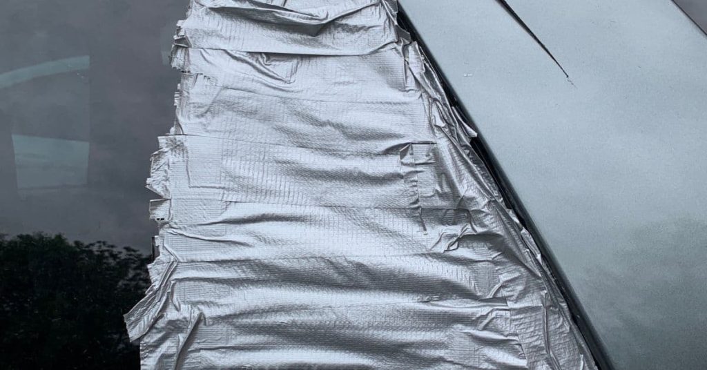 Car window covered with layers of wrinkled silver duct tape