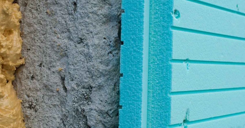 Close-up of blue foam insulation board and rough stucco surface