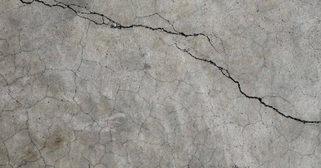 close-up of cracked concrete surface with dark irregular crack