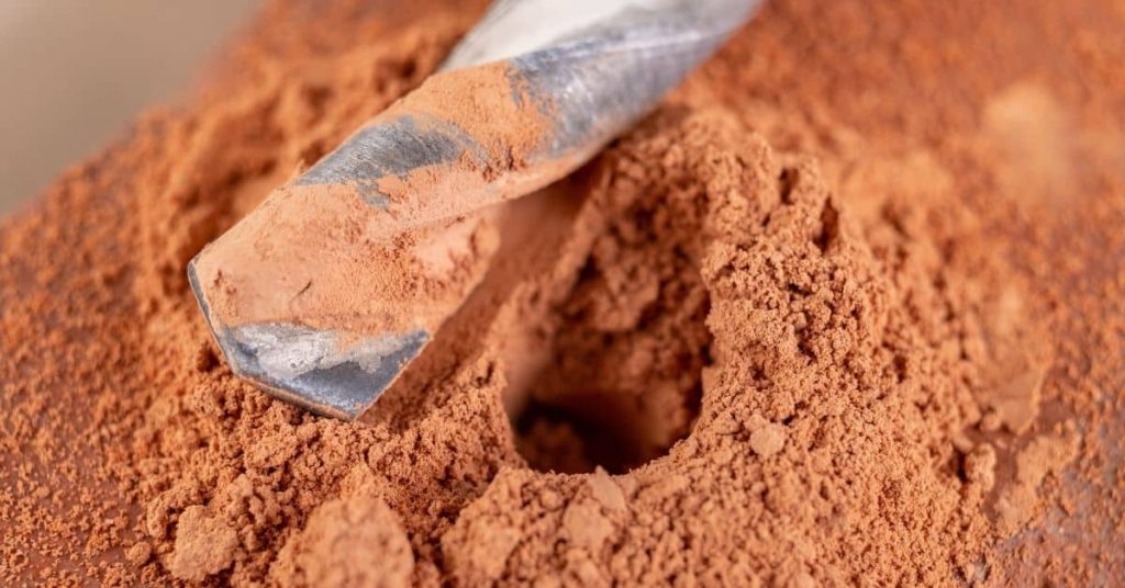 Close up of drill bit covered in fine brick dust