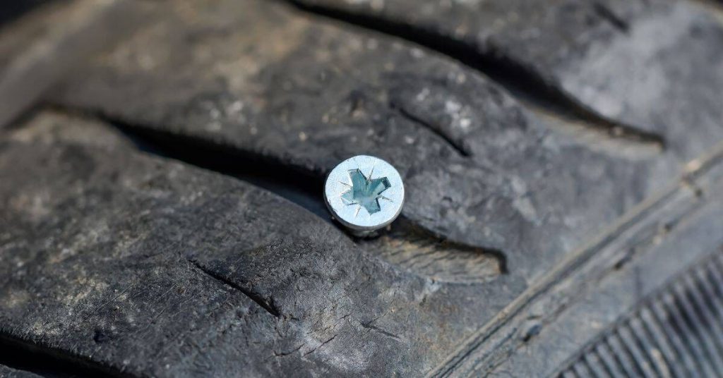Close-up of screw embedded in worn tire tread