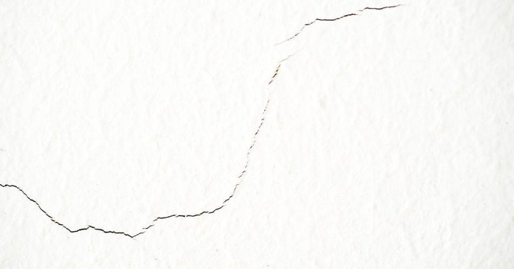 Close-up of thin crack on white stucco wall surface