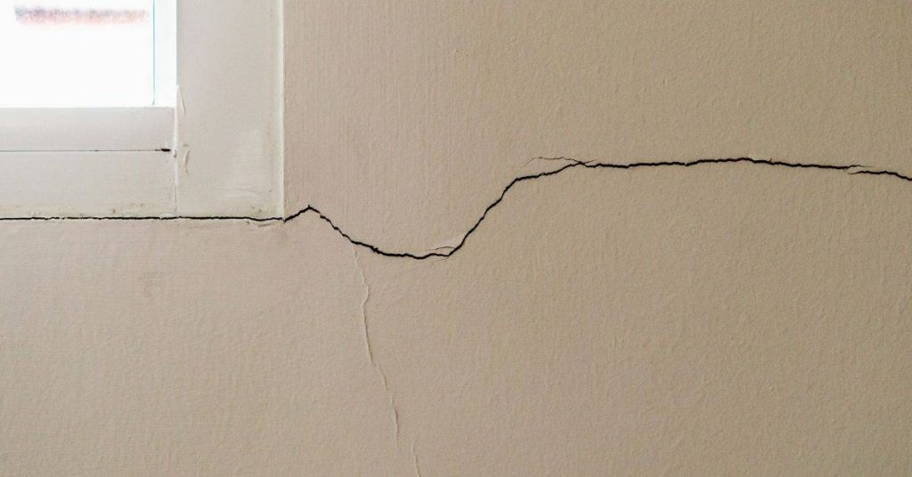 Close-up of wall crack near window frame indoors