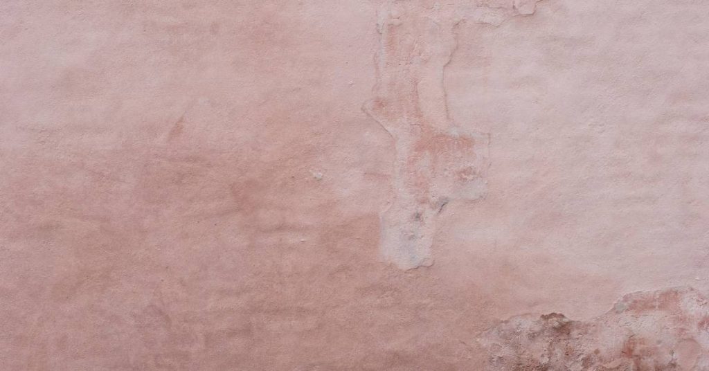 Close-up of weathered pink stucco wall texture