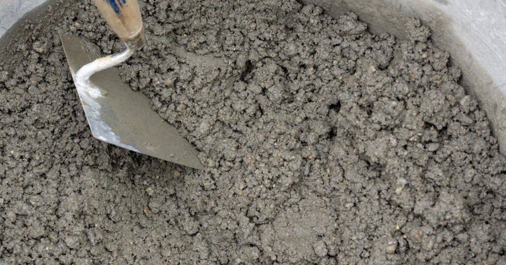 Close-up of wet mortar mix with a metal trowel in bucket