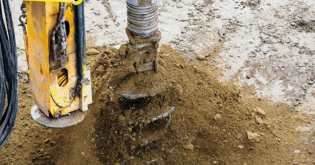 Close-up of yellow earth auger drilling into soil