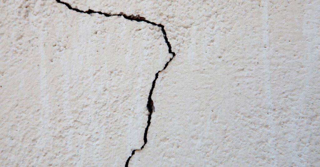 Closeup of cracked white stucco wall surface