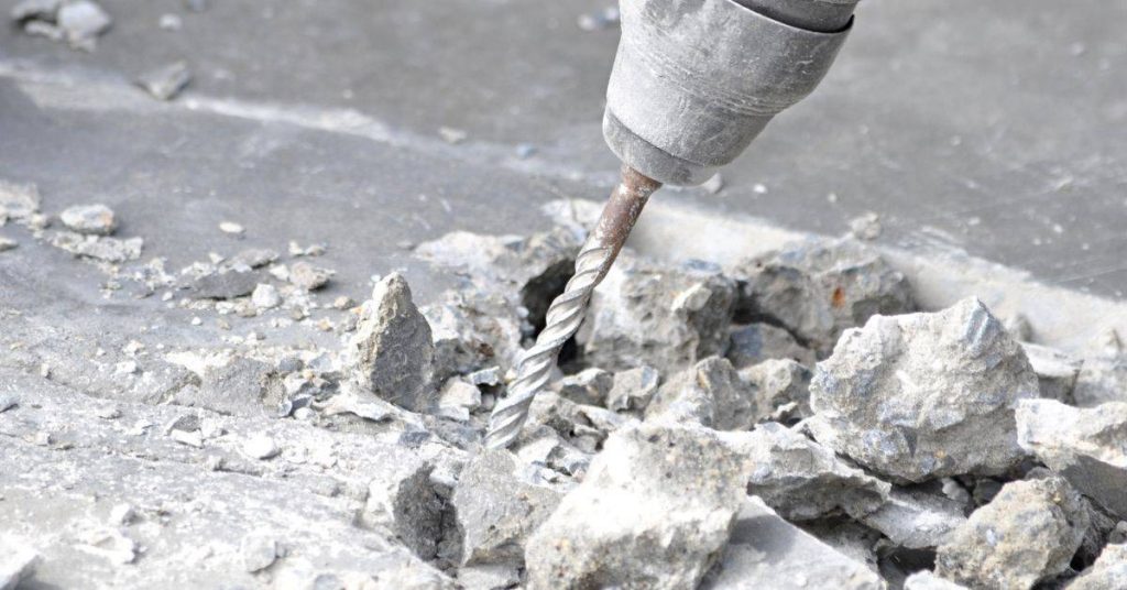 closeup of drill bit breaking concrete surface