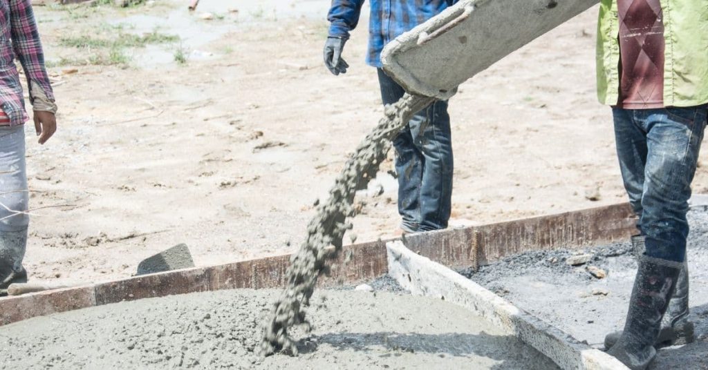 Concrete being poured into wooden slab form with workers