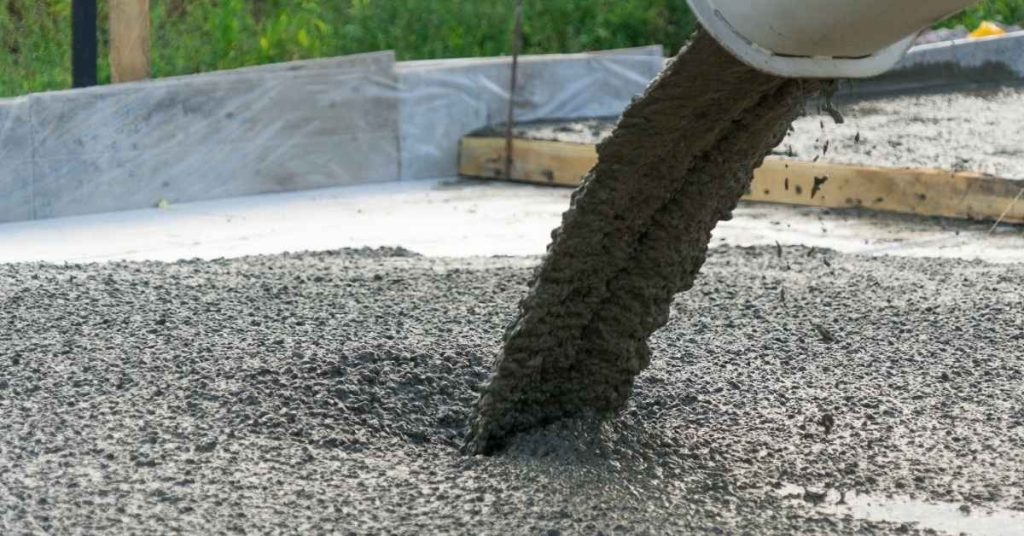 Concrete being poured onto slab framed by wood
