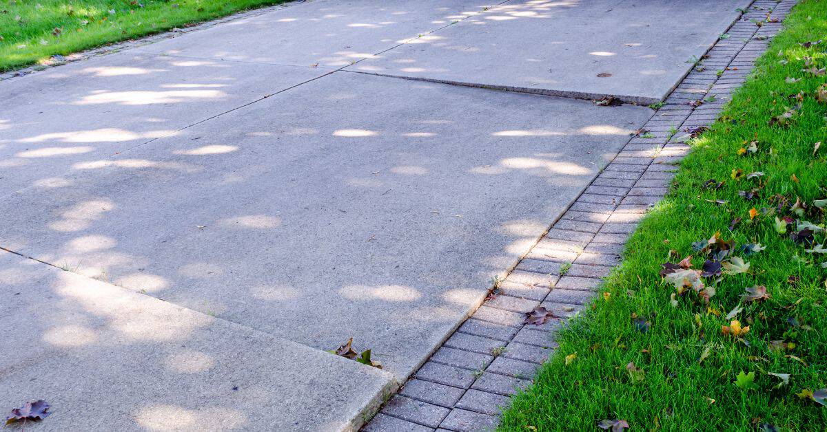 Concrete driveway with brick border alongside green grass