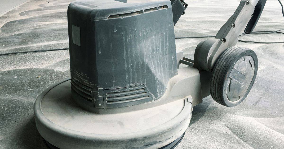 Close-up of a concrete floor grinder machine on dusty floor