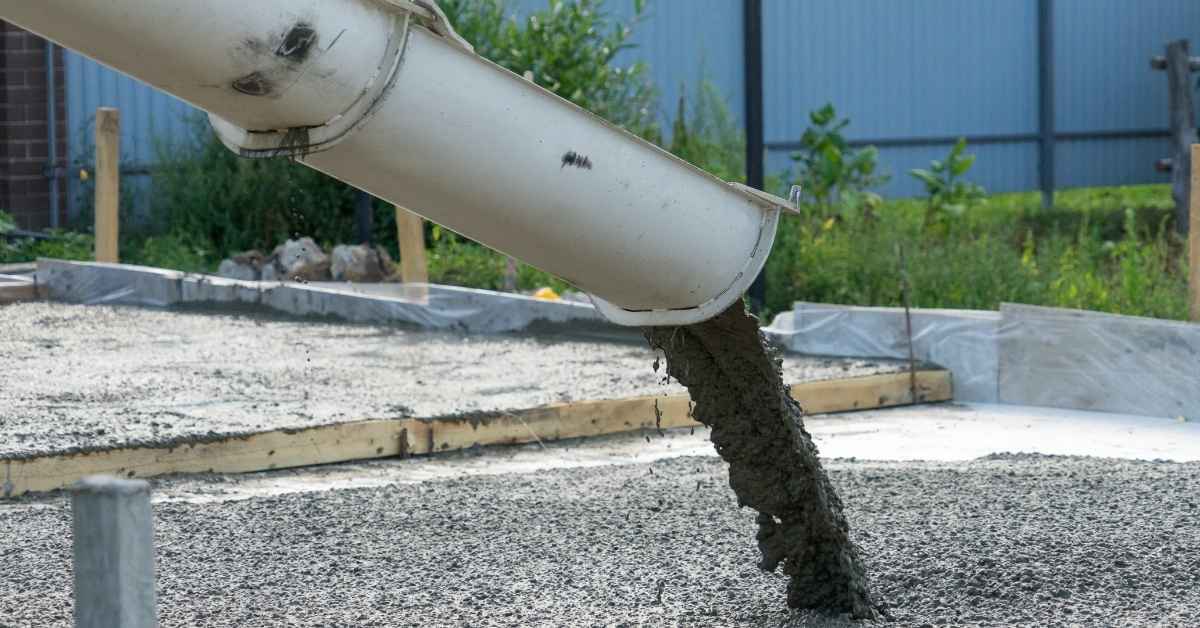 Concrete pouring from chute onto slab foundation