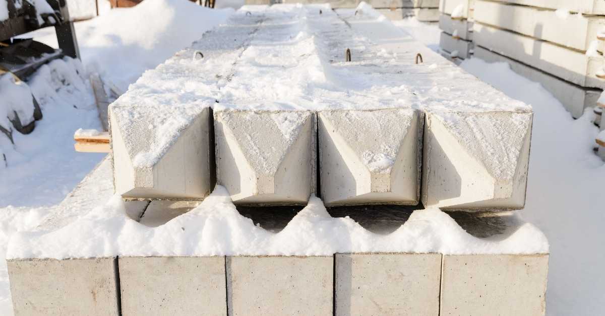stacked precast concrete beams covered in snow outdoors