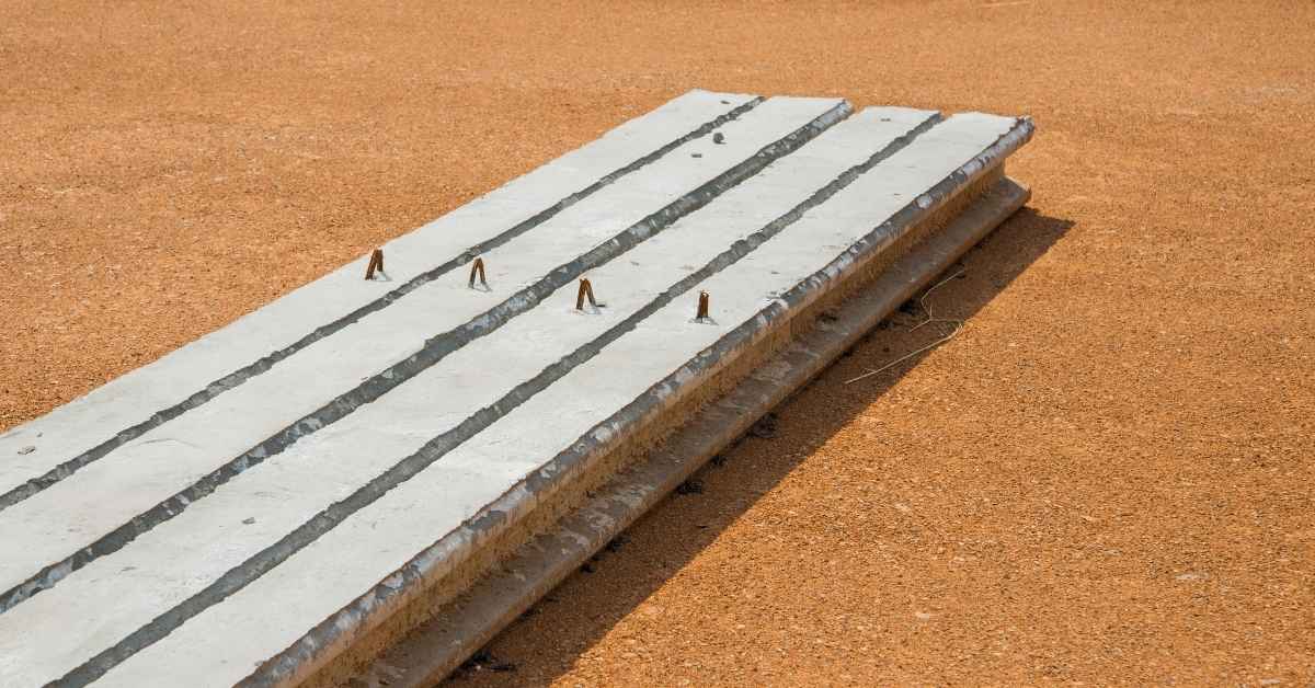 Concrete precast panel with exposed rusty rebar on gravel