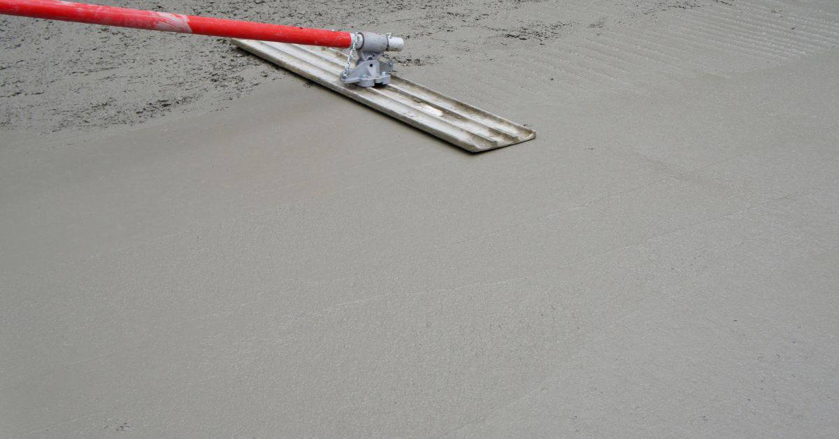 Concrete surface being smoothed with screed tool
