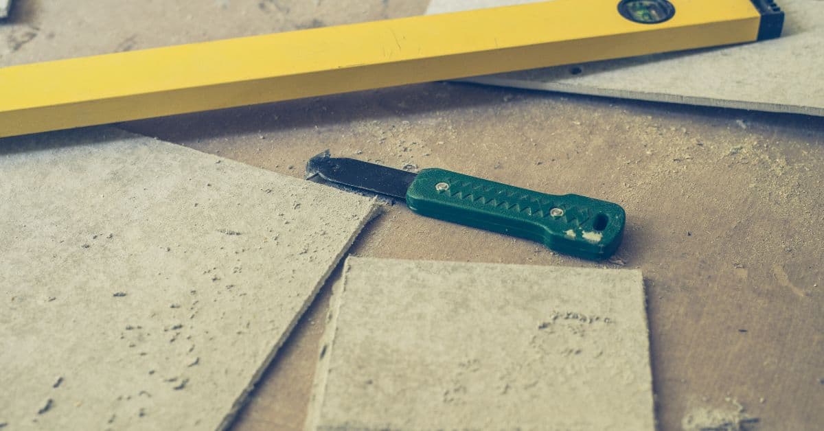 utility knife with green handle and cut concrete board pieces