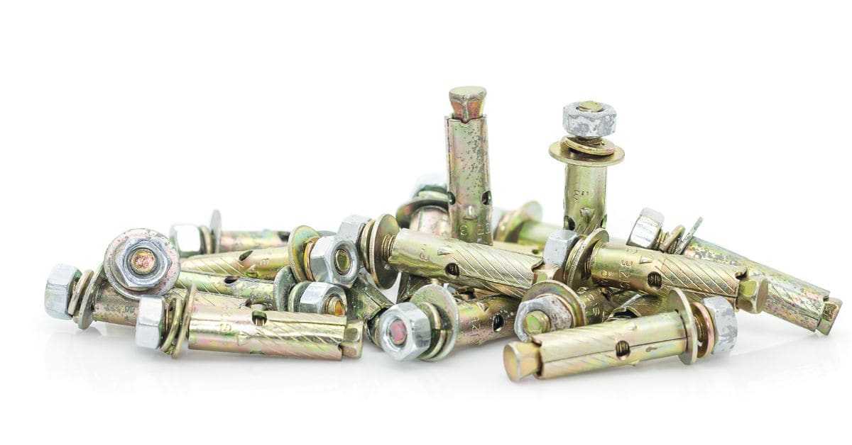 Pile of metal concrete expansion anchor bolts on white background