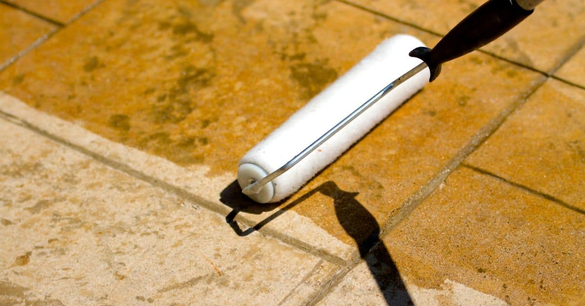 roller applying sealant to stained concrete pavers