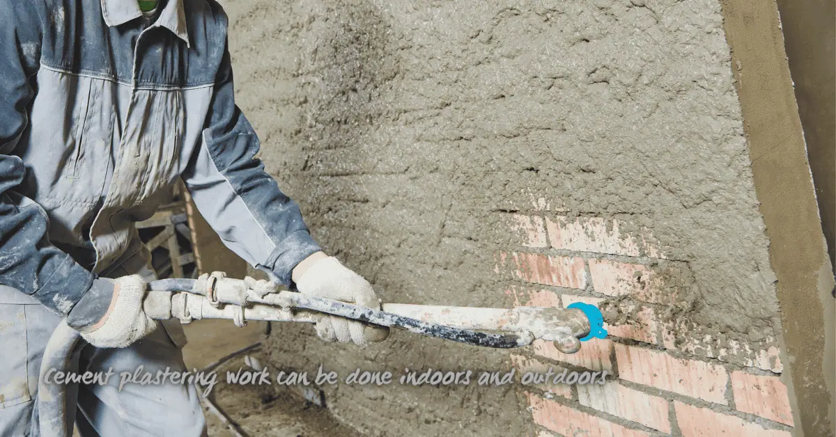 Worker spraying cement plaster onto block wall