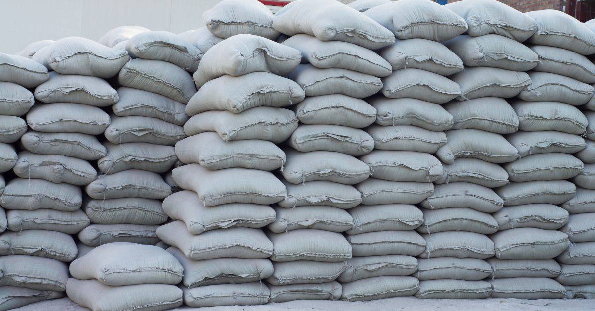 Large stack of gray cement bags piled outdoors