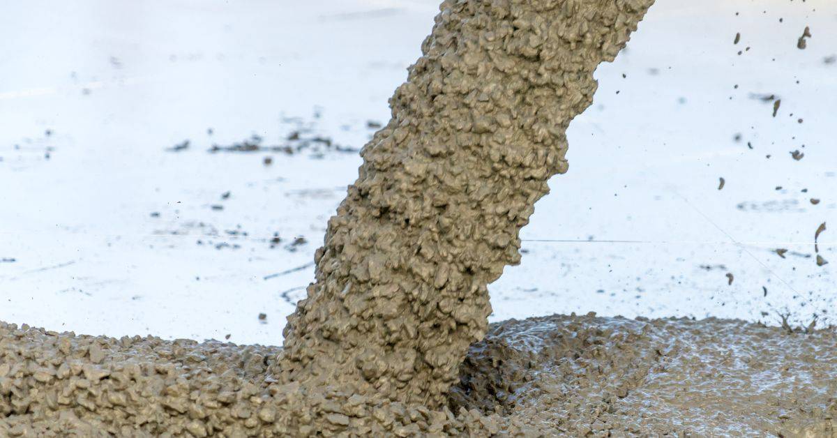 Wet concrete being poured onto flat surface