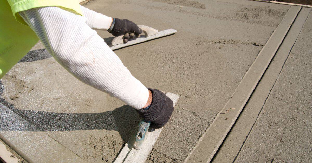 Person smoothing fresh concrete with hand tools