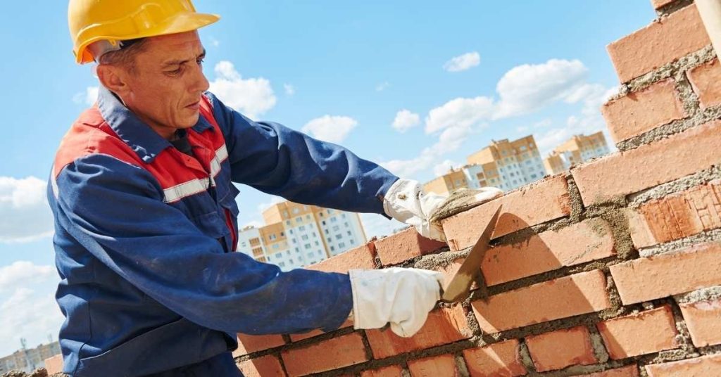 Construction worker cutting joint in brick wall outdoors