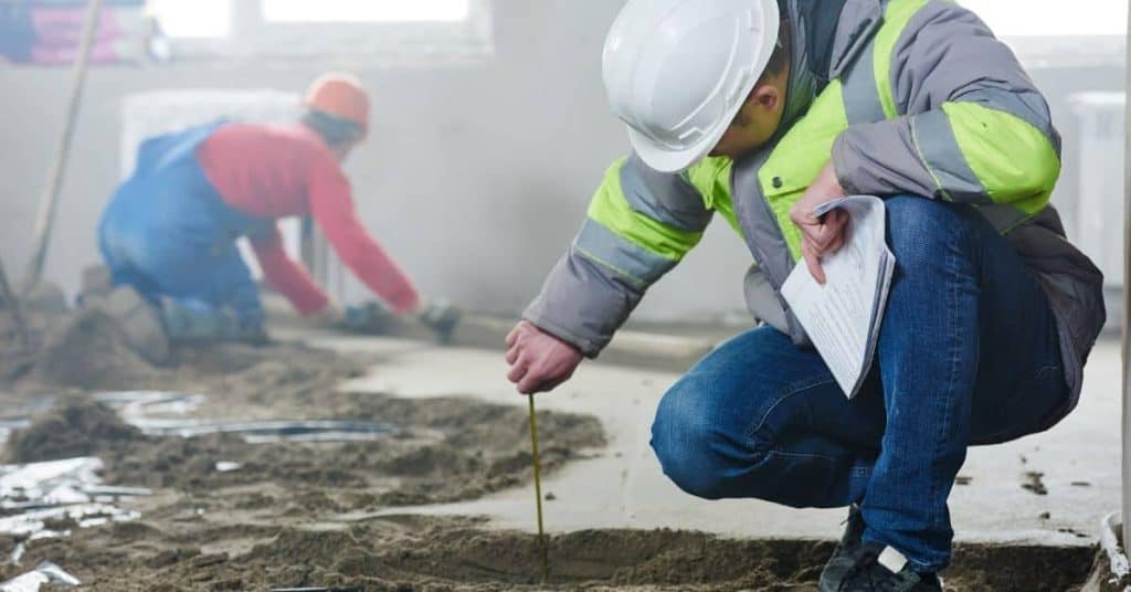 Construction worker measuring concrete slab with tape measure