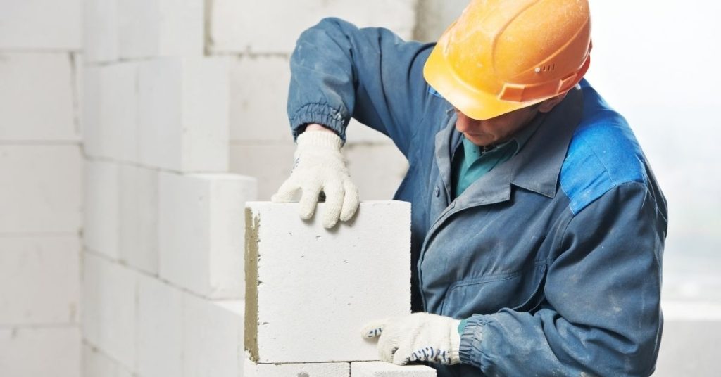 Construction worker placing foam concrete blocks on wall