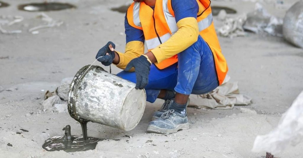 Construction worker pouring concrete from bucket onto floor