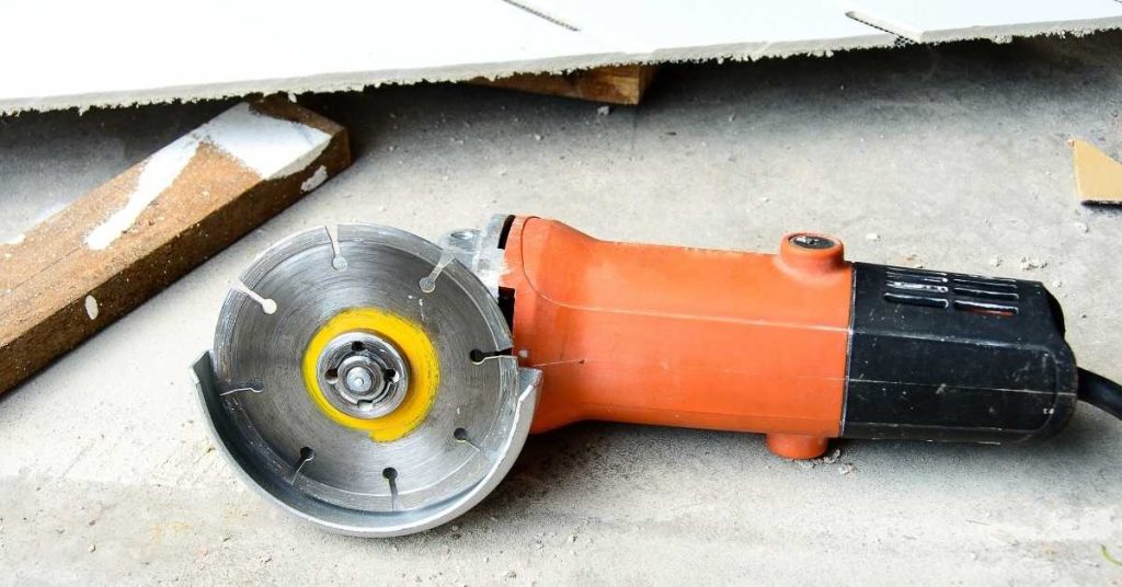 Corded angle grinder lying on dusty concrete floor