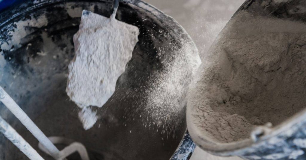 Dry concrete powder falling into mixing bucket