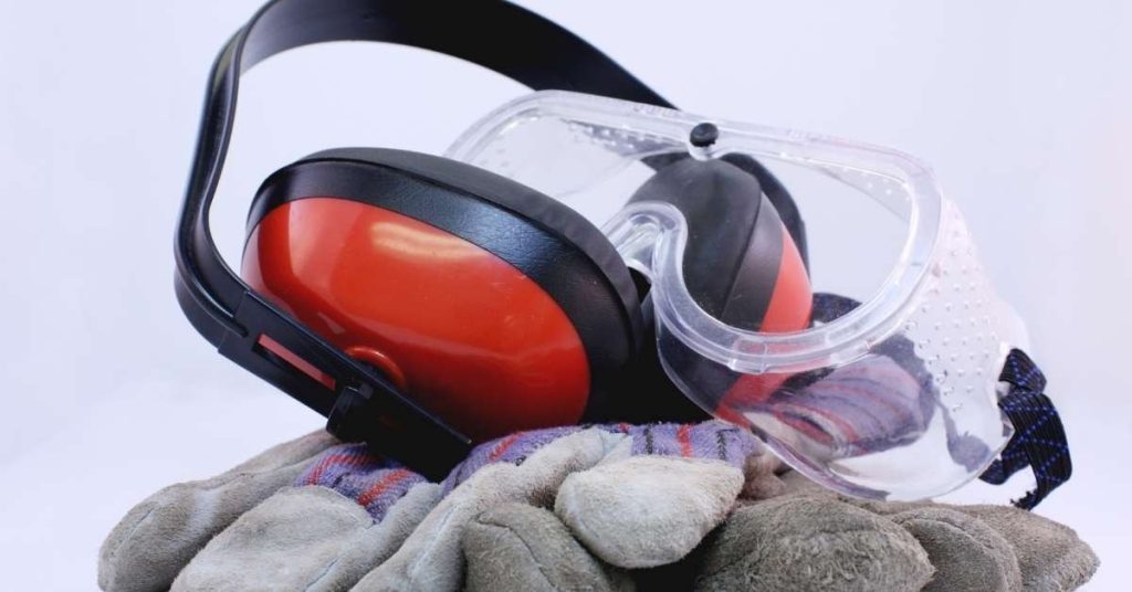 earmuffs safety glasses and work gloves on white background