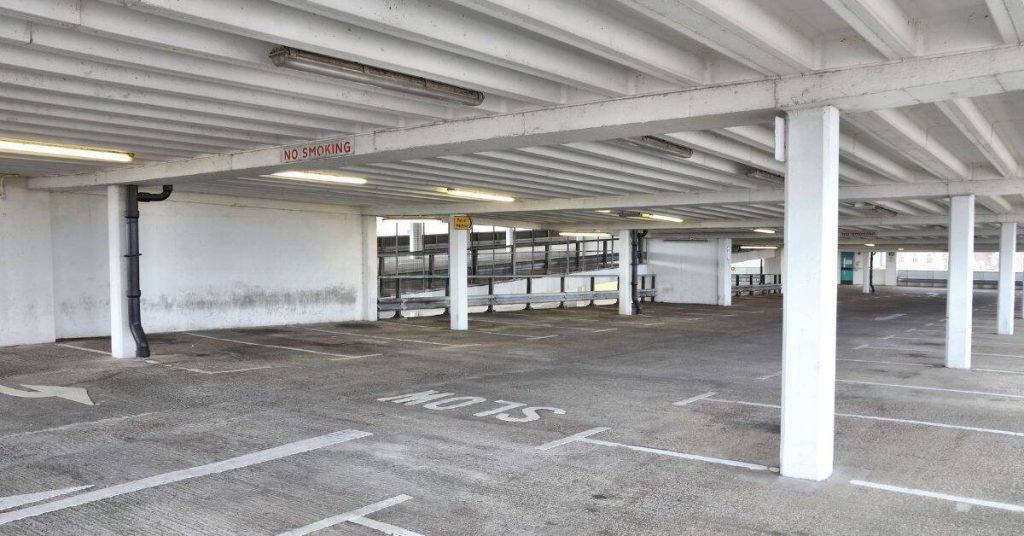 Empty concrete parking garage with support columns and ceiling beams