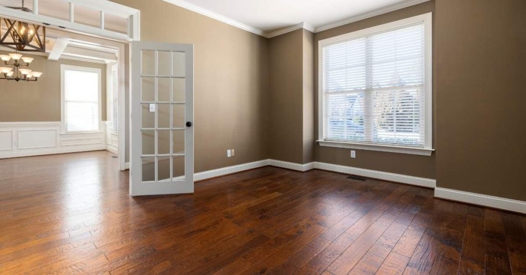 Empty room with finished hardwood floor and white trimmed window