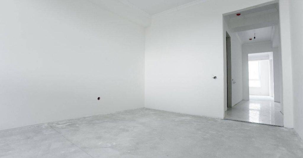 Empty room with white plastered walls and concrete floor
