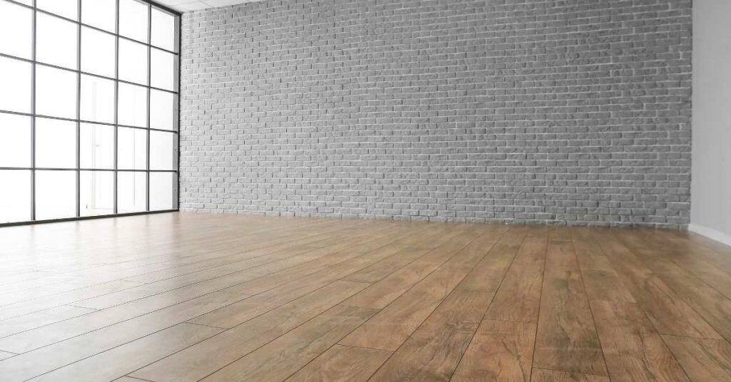 Empty room with wooden plank flooring and large window wall