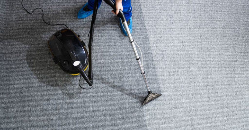 Person using carpet cleaning machine on gray carpet floor