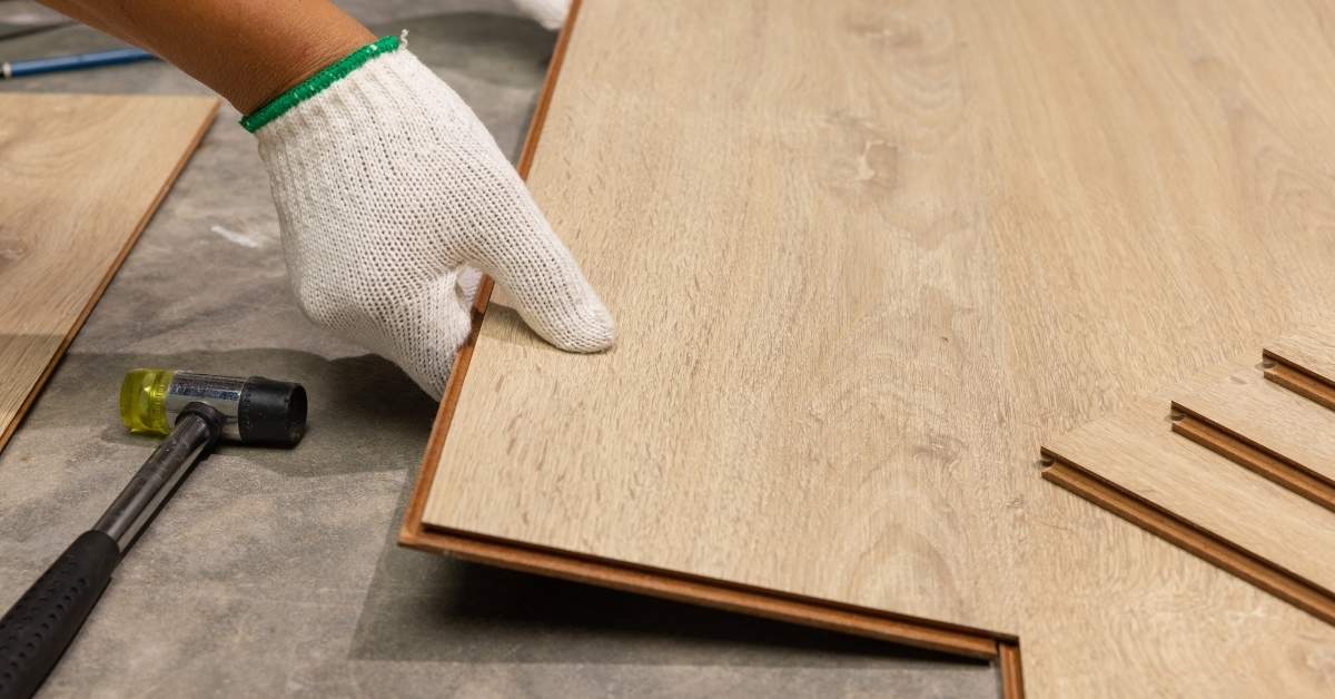 Hand wearing white glove installing laminate floor plank