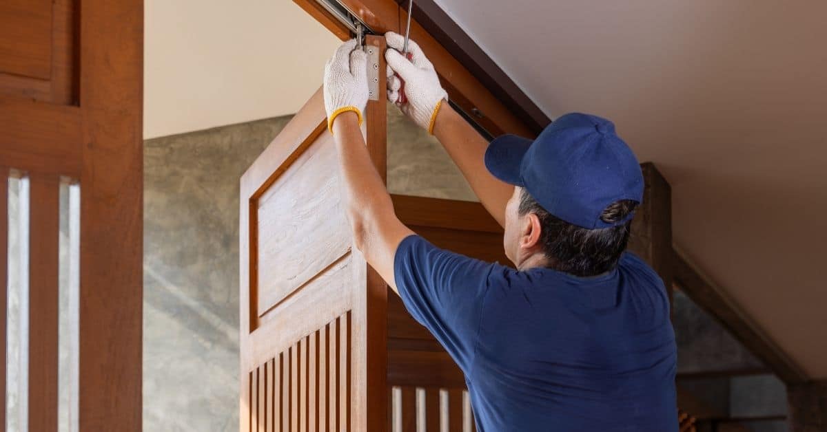Man installing wooden bifold door in interior space