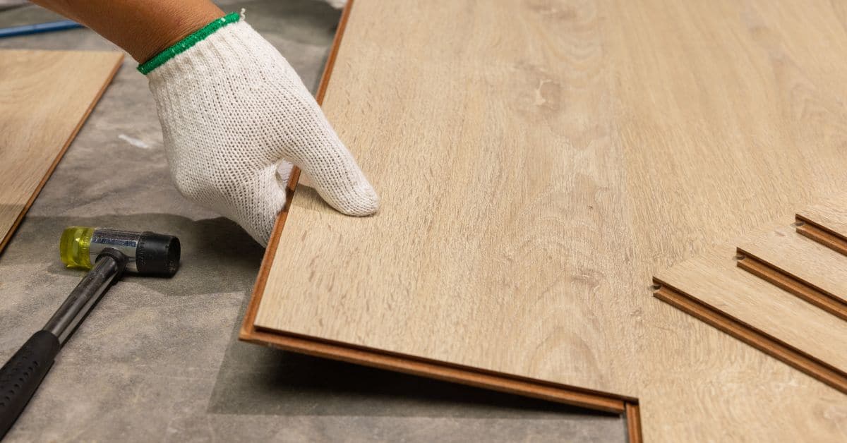 Hand in white glove holding laminate flooring plank