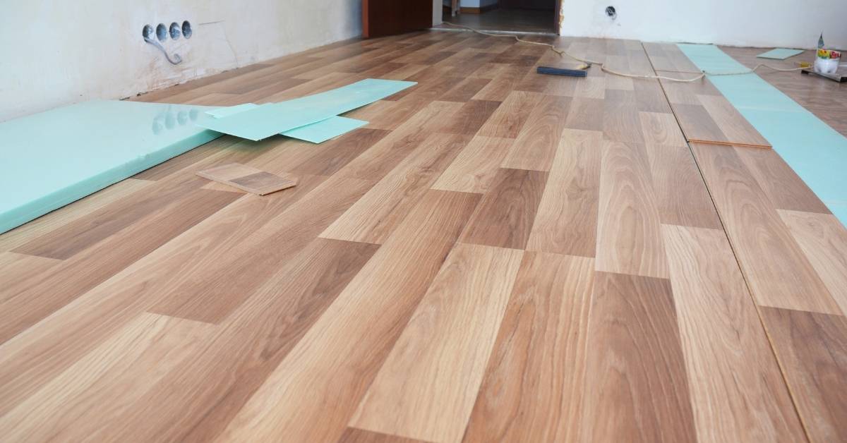 Partially installed laminate flooring with underlay foam visible