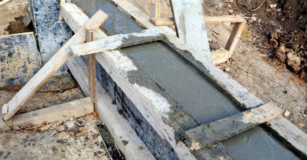 Fresh concrete poured into supported wooden forms outdoors