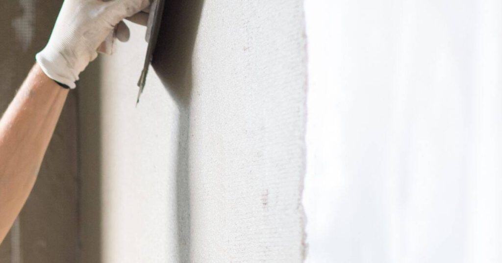 Hand applying plaster to wall with trowel